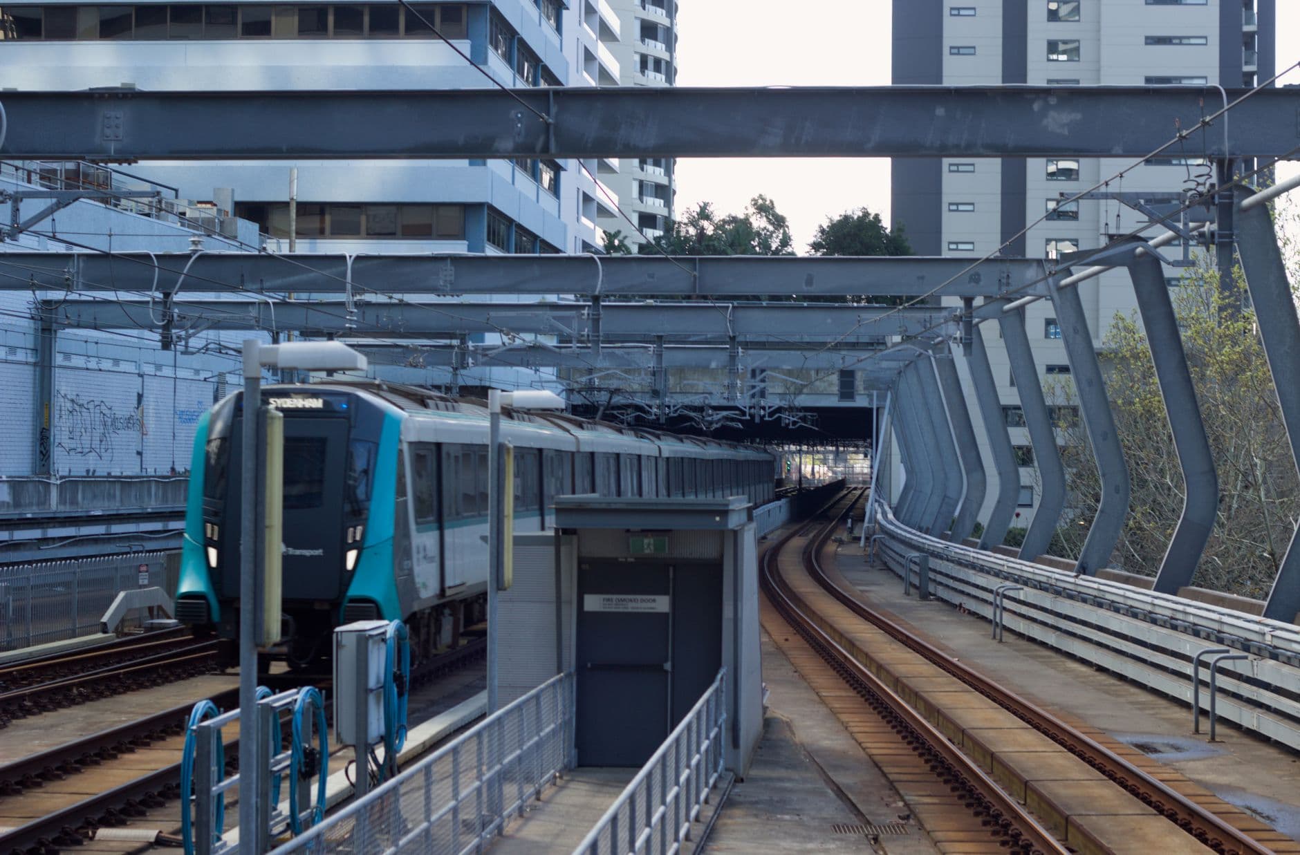 Sydney Metro train entering Chatswood Station in New South Wales, featuring urban architecture.