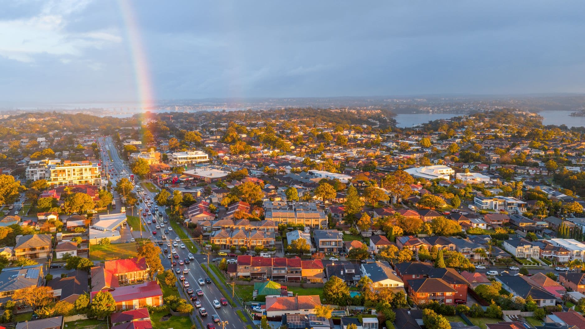 Stunning aerial view of suburban Sydney with a vibrant rainbow and clear skies.