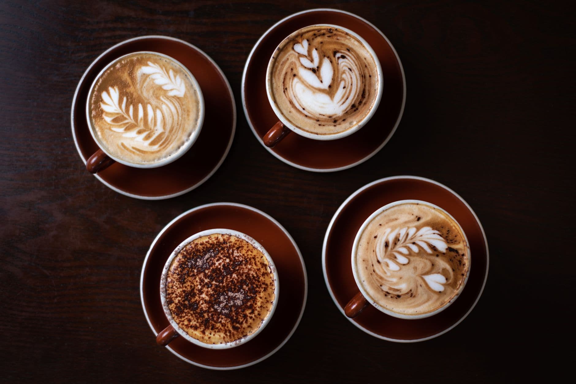 Four beautifully crafted latte art designs in a Sydney coffee shop, showcasing coffee culture.
